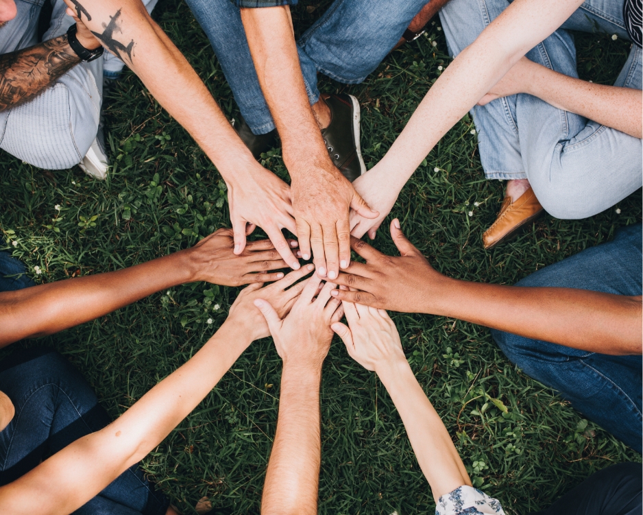 Mehrere Hände liegen übereinander als Symbol für Teamwork und Zusammenarbeit.