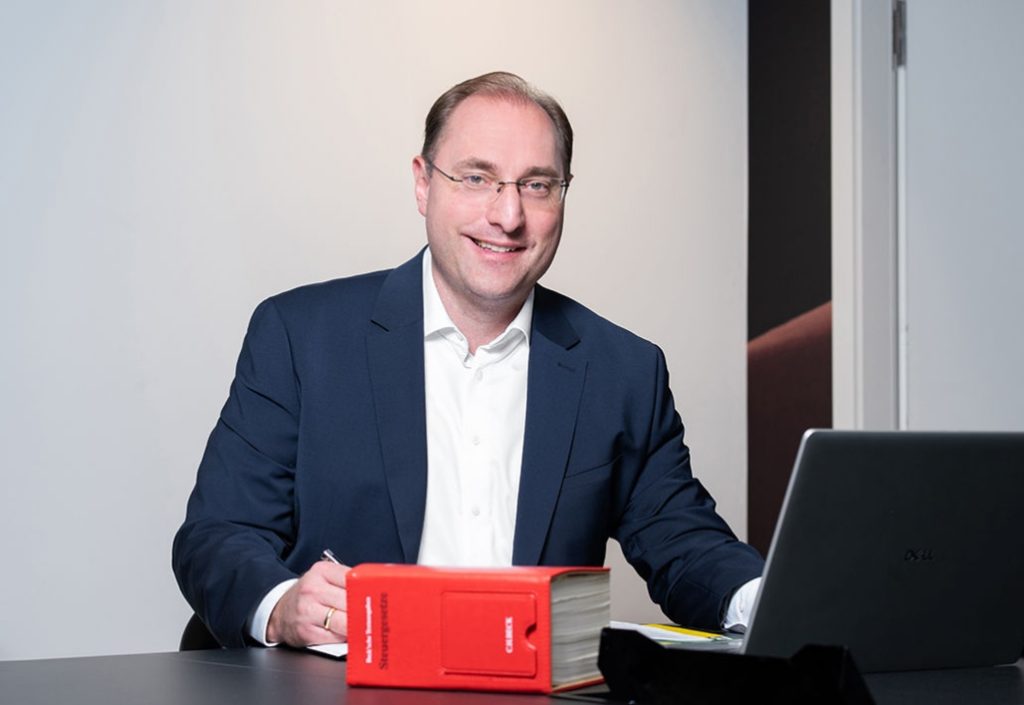 Porträt Steuerberater Hoffmann in Businesskleidung vor einem neutralen Hintergrund.
