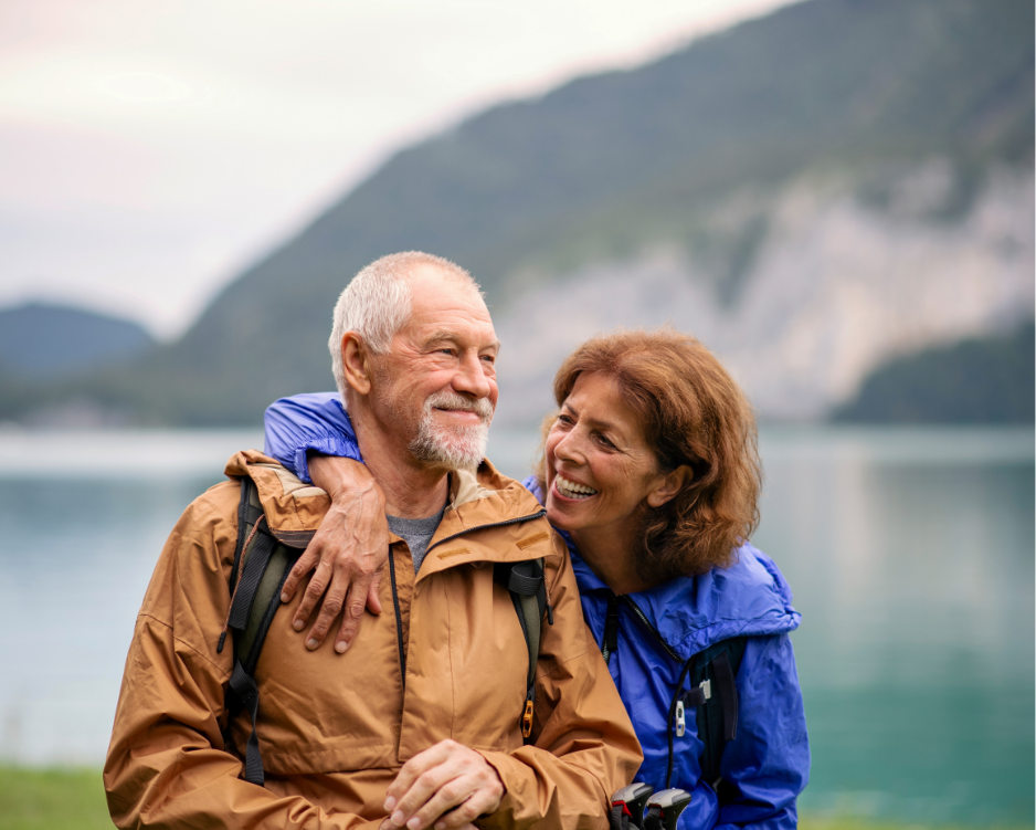 Zwei Personen stehen gemeinsam am Ufer eines Sees vor einer Berglandschaft.